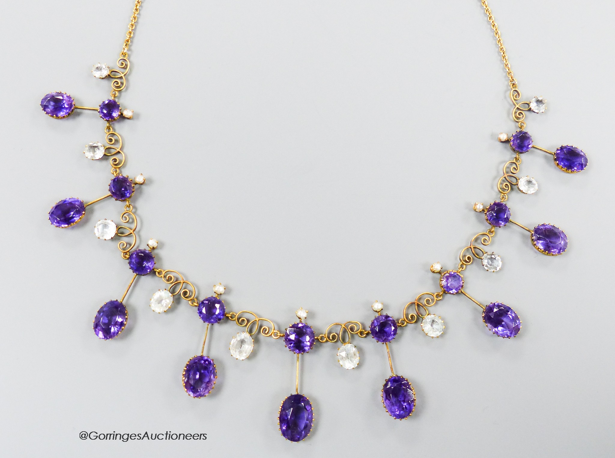 An early 20th century yellow metal, amethyst, aquamarine and seed pearl set drop fringe necklace, with later 375 clasp, 46cm, gross weight 18.6 grams.